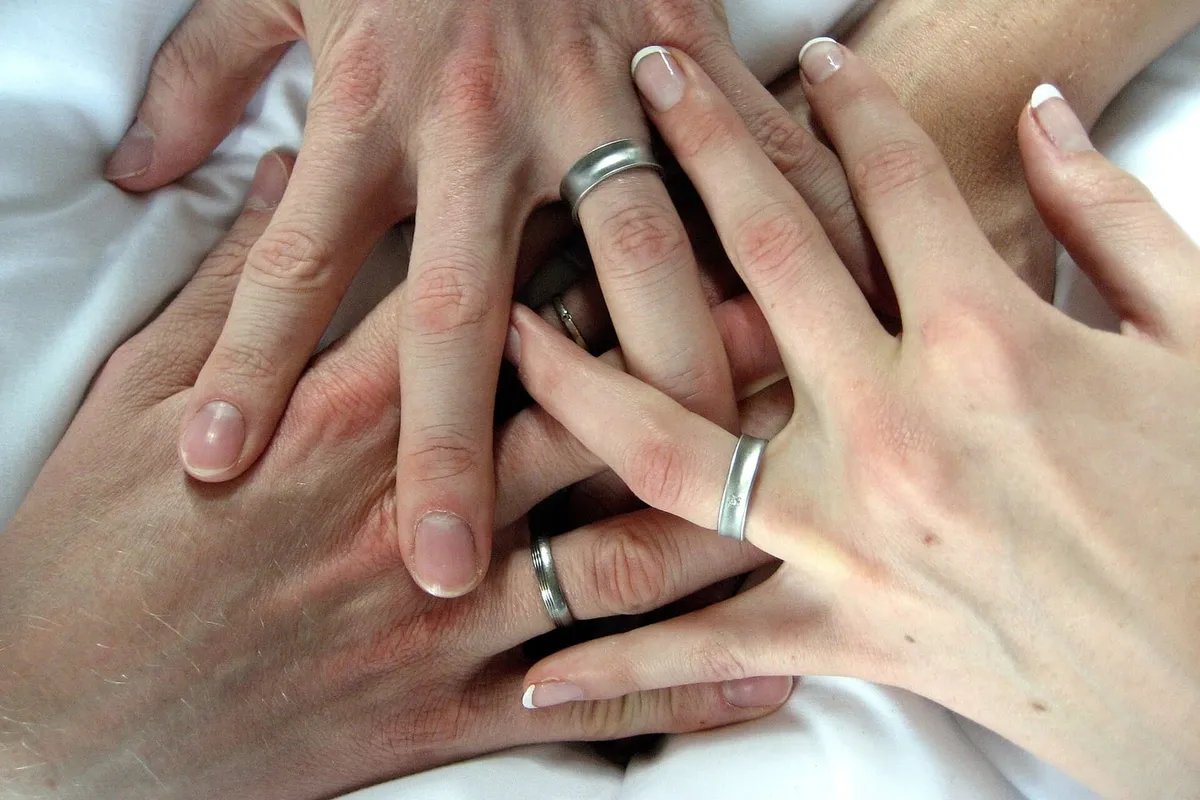 Plain bands worn on two hands resting on white linen