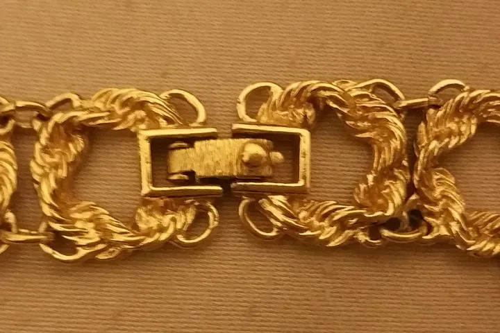 A gold bracelet chain photographed in close up with its box clasp open