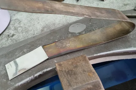 A metal strip with one end polished bright next to the dull, tarnished section